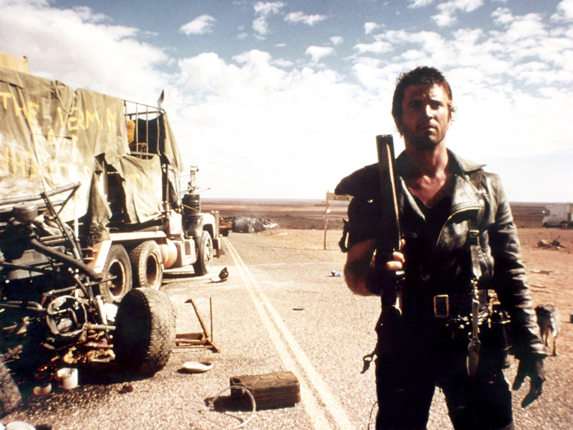 Max holding up a shotgun while on the road in Mad Max 2 The Road Warrior