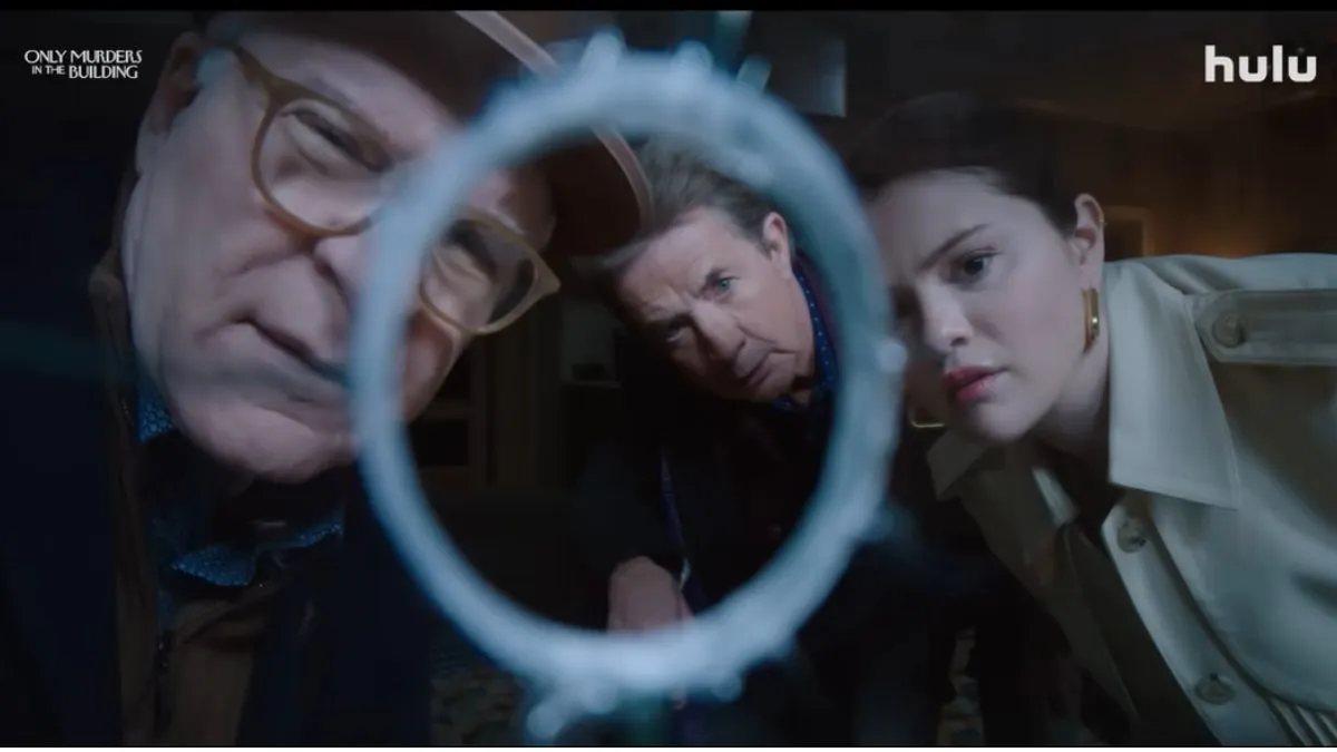 Screenshot from Only Murders in the Building Season 4, showing the three main characters staring through a bullet hole