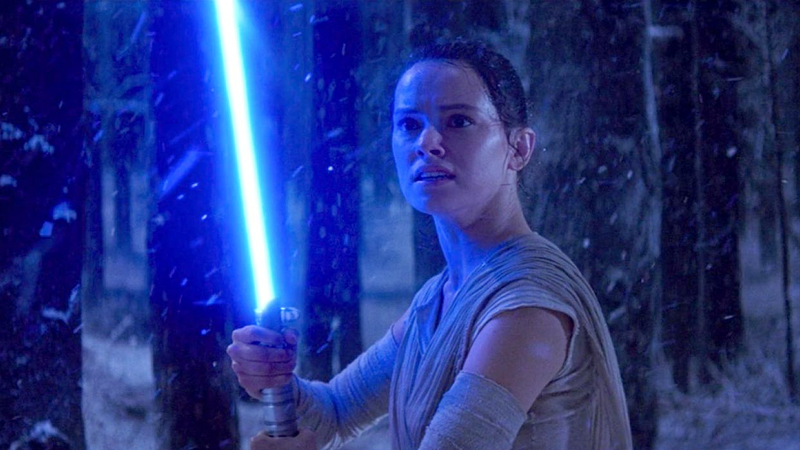 Rey holding her blue lightsaber in Star Wars: The Force Awakens