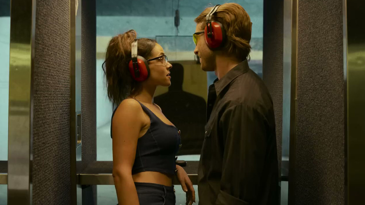 Hit Man, the male and female at a gun range, wearing ear protectors.