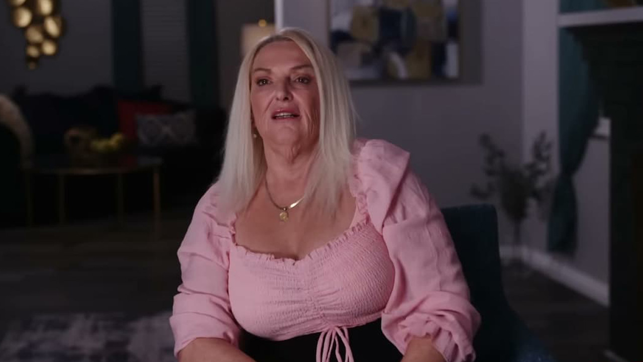 Angela from 90 Day Fiance, a blonde-haired woman sitting, wearing a pink top
