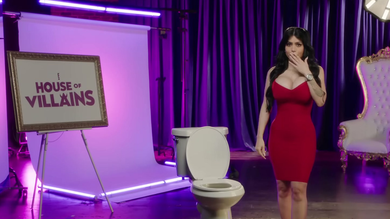 House of Villains Season 2's Larissa Lima, standing near a toilet.