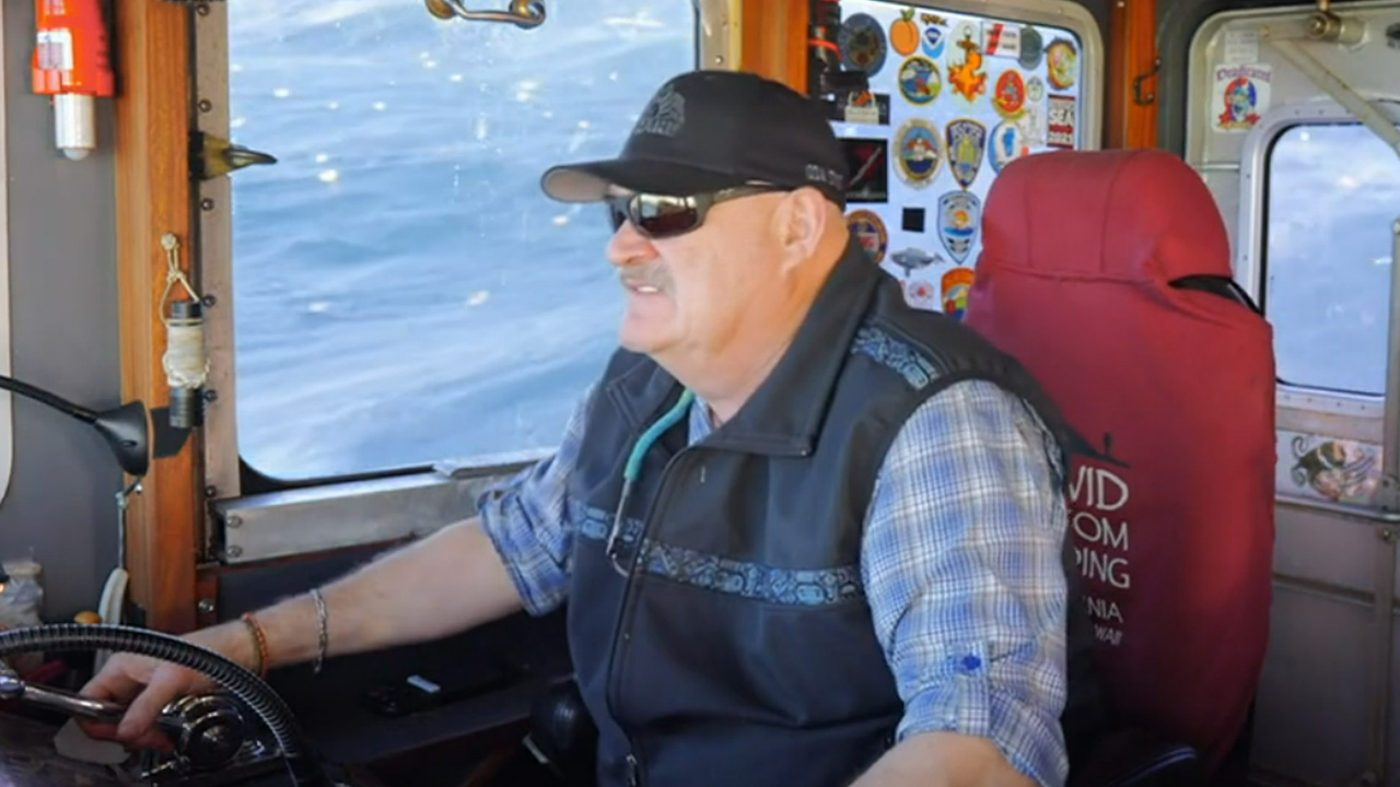 Deadliest Catch's Keith, in sunglasses and a baseball cap, sailing his vessel.