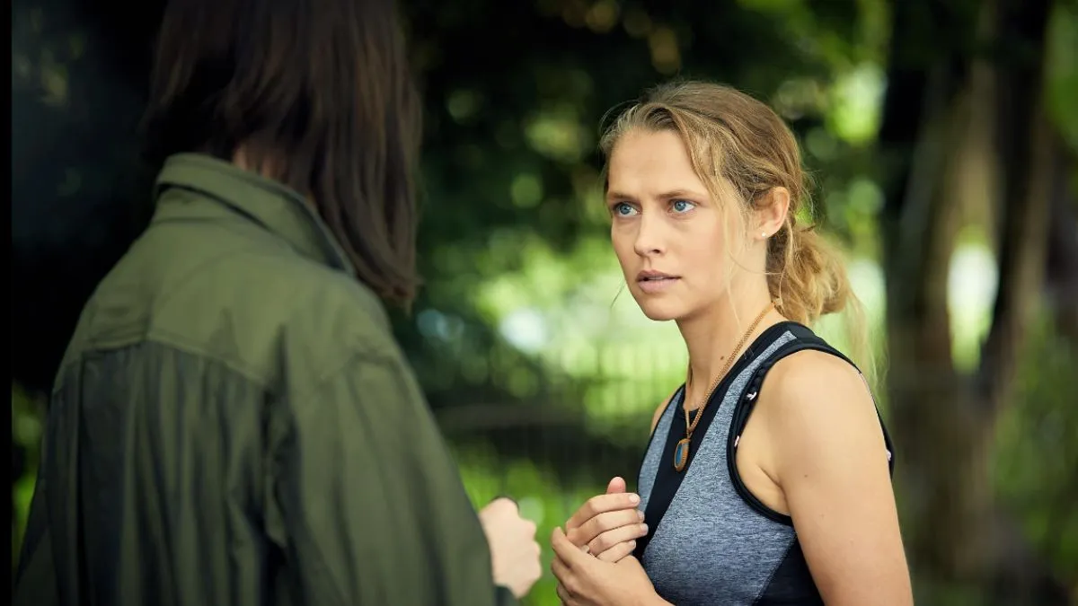 Diana in Conversation in A Discovery of Witches, looking suspicious as she speaks to a woman in a green jacket