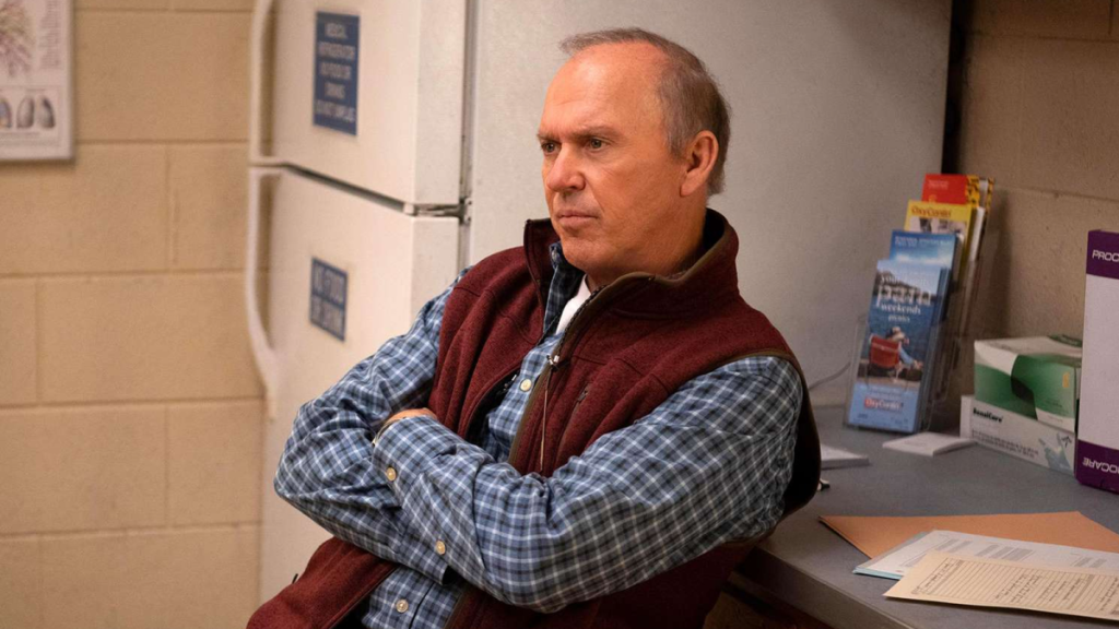 Michael Keaton as Dr. Samuel Fennix in Dopesick, crossing his arms in a building's kitchen