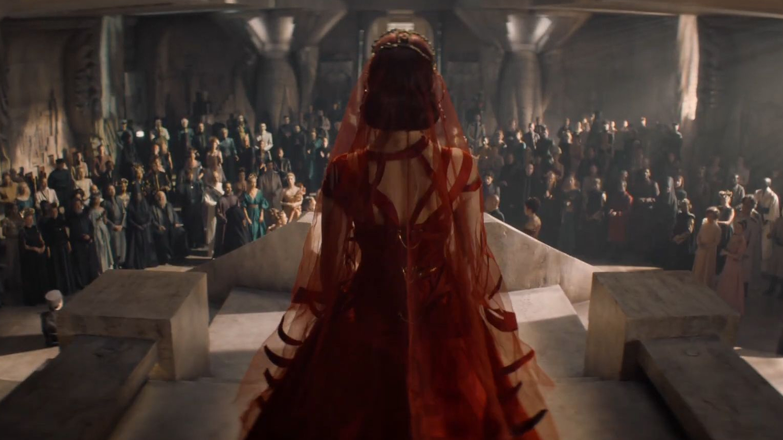 A woman in a red dressing standing before a crowd in the Dune: Prophecy trailer