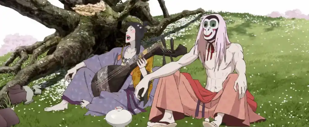 An entertainer strums a string3ed instrument beneath a tree beside a masked man 