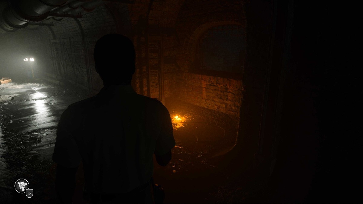 An orange light sits on the ground beside a barricade in a damp tunnel