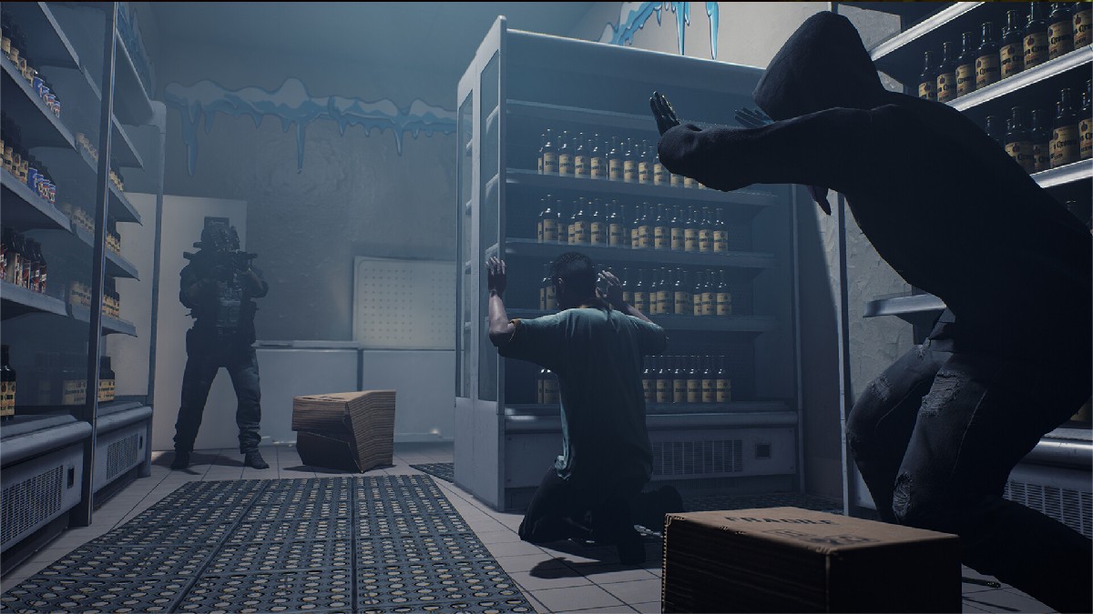 Image of two men coming to kneel on the ground in a store room as a man points a gun at them