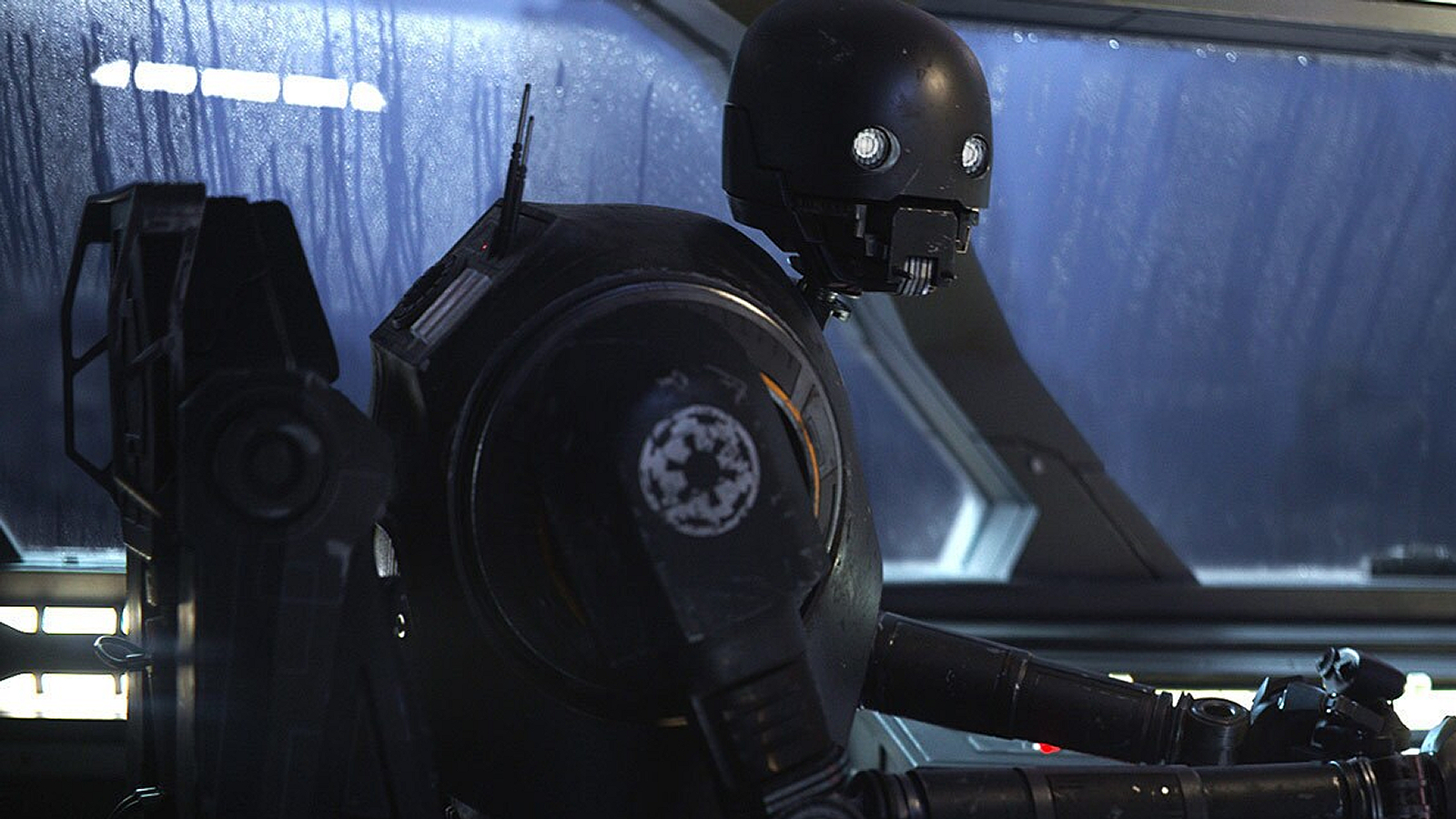 K-2SO in a cockpit with rain-spattered windows in Rogue One: A Star Wars Story