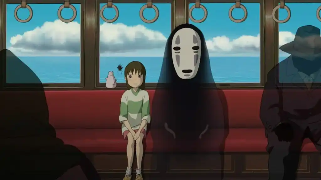 A young girl sits on a train beside a masked spirit with the ocean behind them in anime movie Spirited Away