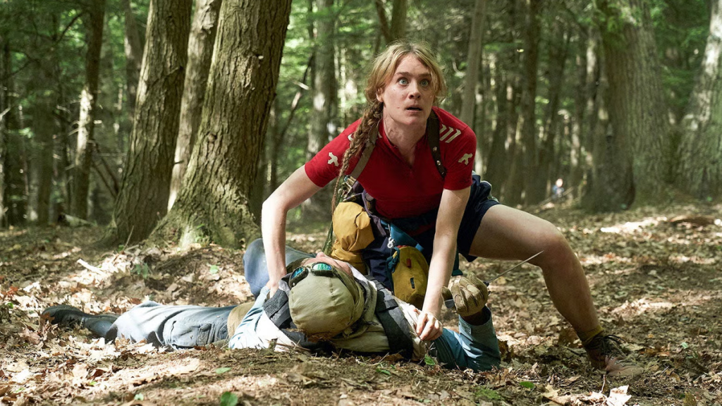 Mackenzie Davis as Kirsten Raymonde in Station Eleven, with a woman holding a man to the ground on a forest floor