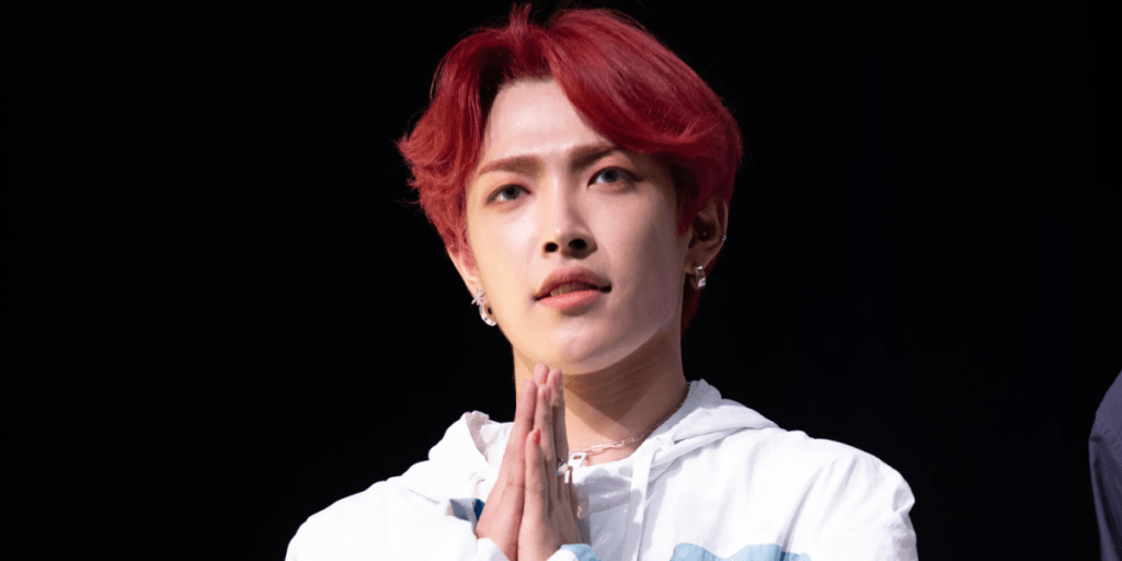 Image of Hongjoong holding his hands together against a black background