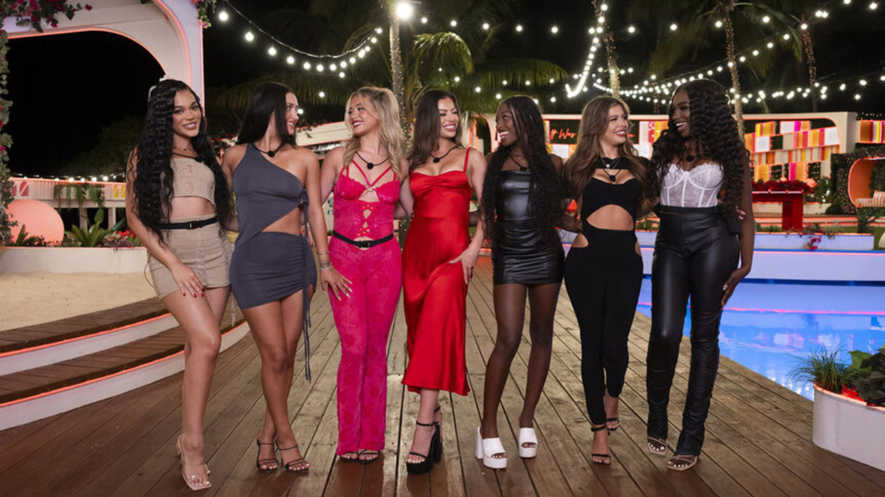 Several female contestants from Love Island, standing next to a swimming pool.