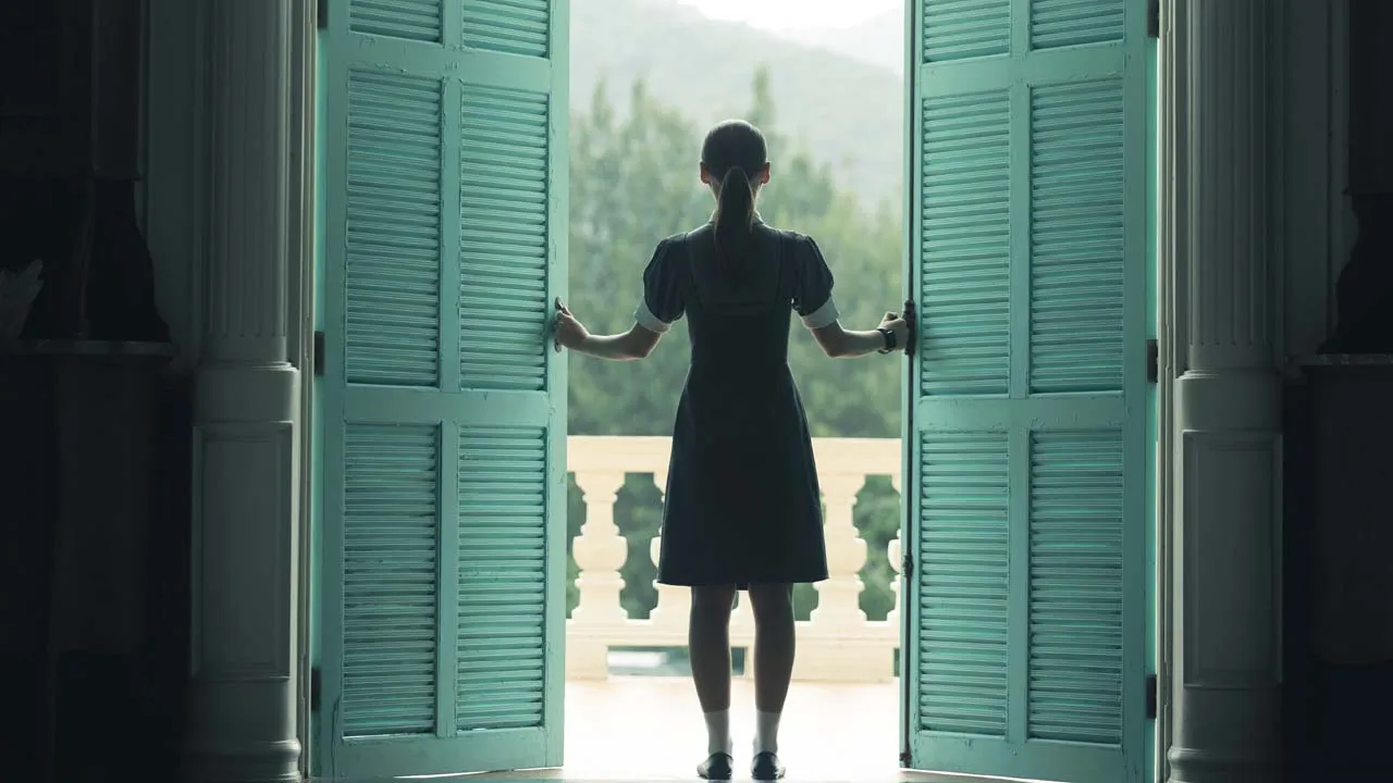 Master of the House, a woman opening shutters that lead onto a balcony, viewed from behind.