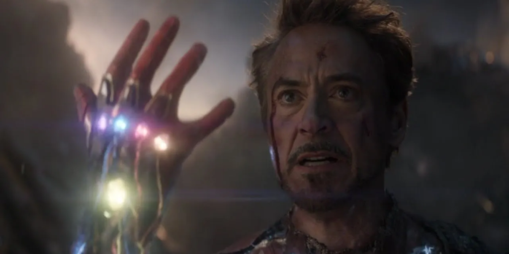 An unmasked Iron Man wearing the Infinity Gauntlet holds up his hand in Avengers: Endgame.