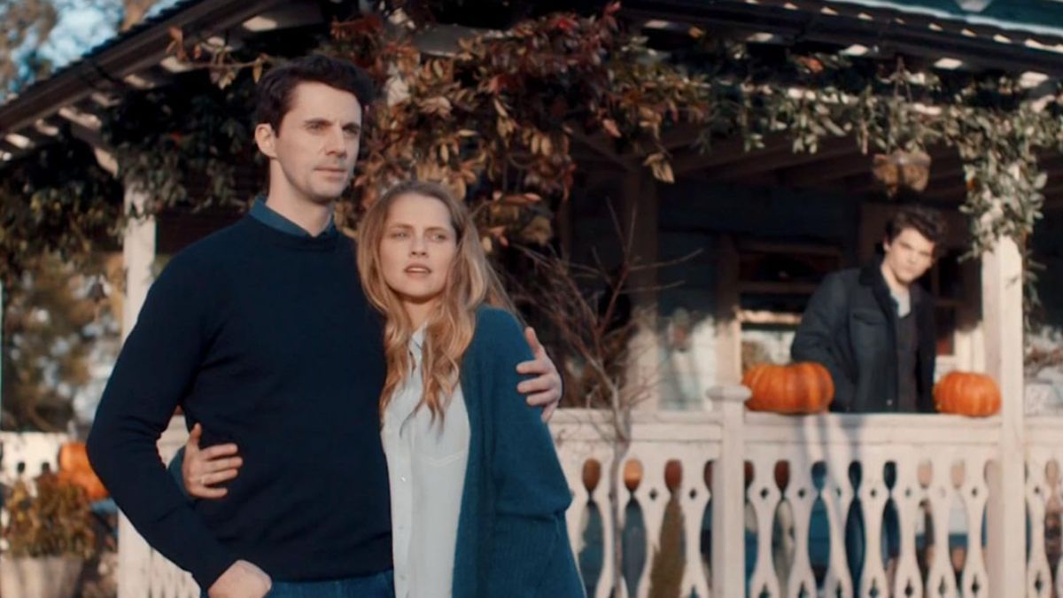 Diana and Matthew from a Discovery of Witches, standing in front of a white picket fence