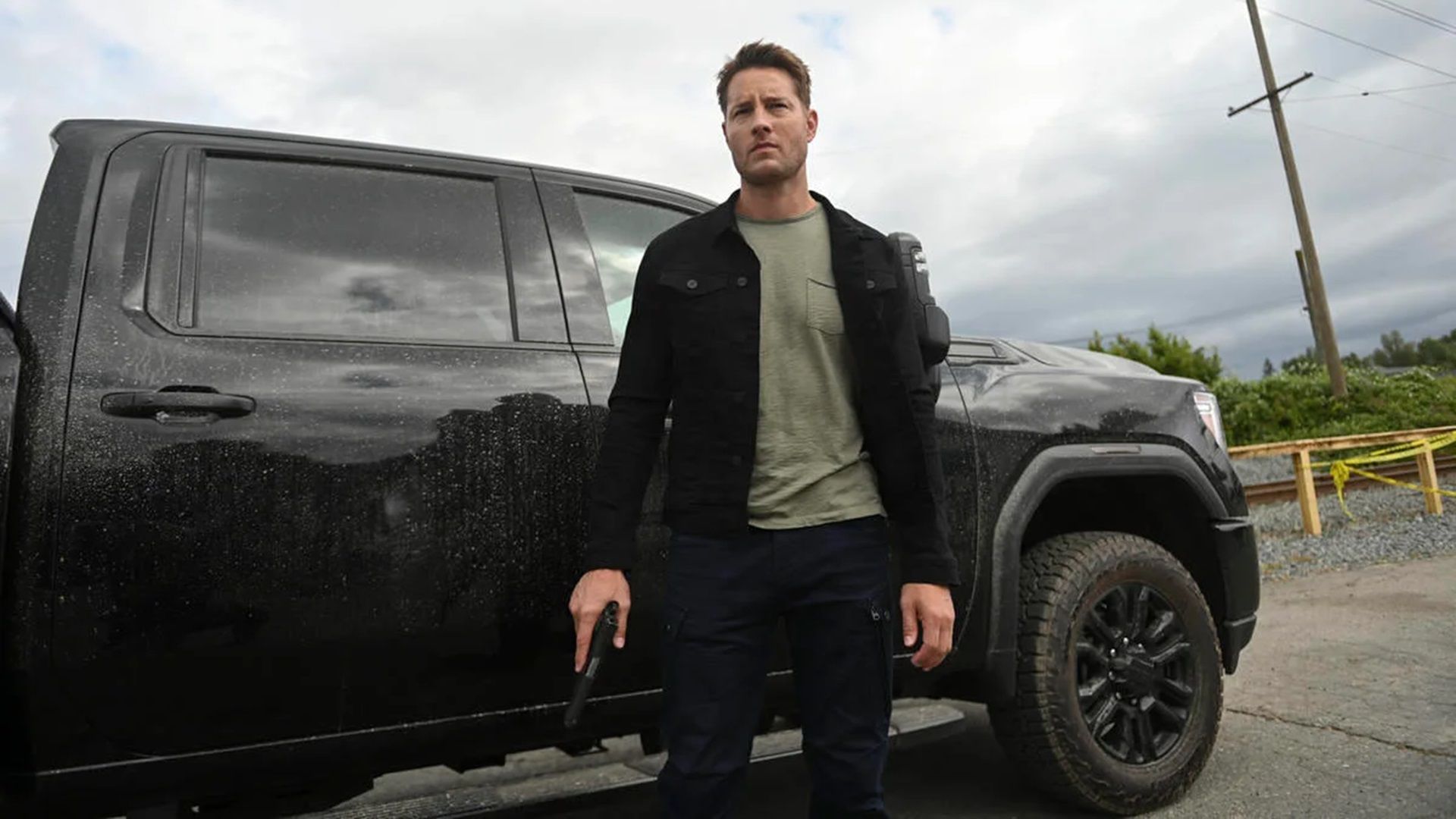 Colter holds a pistol next to a black truck