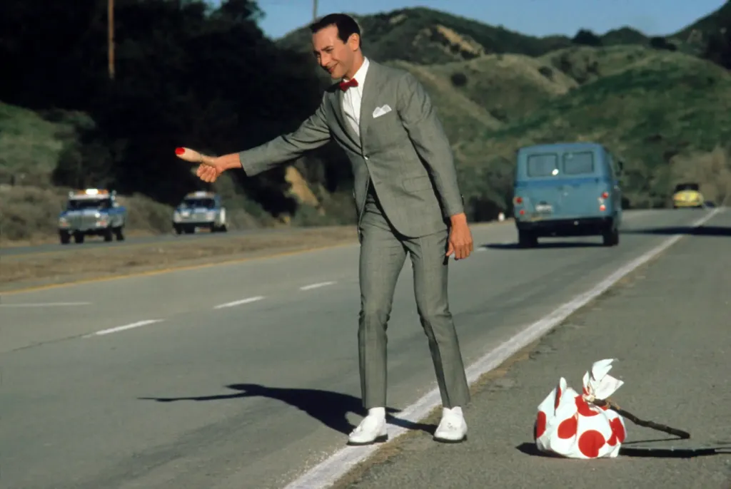 Screenshot of Paul Ruebens Hitch Hiking in Pee-Wee's Big Adventure from Academy Museum as part of an article about the best TIm Burton movies.