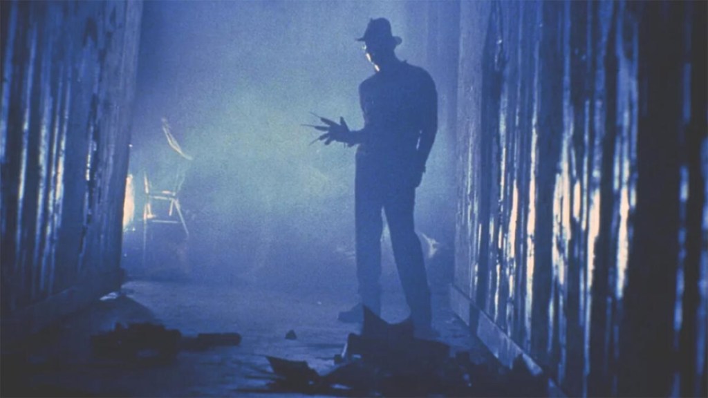 Freddy Krueger stands in a darkened hallway  as part of an article about the best horror movies on streaming.