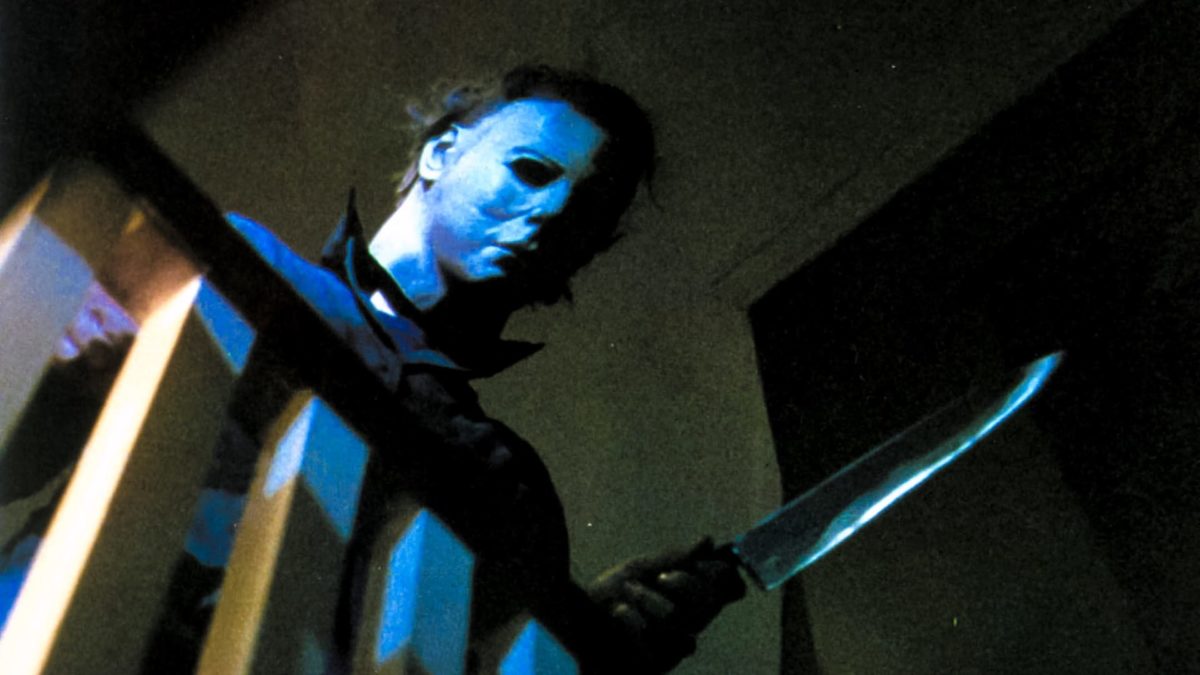 Michael Myers looks over a railing while holding a knife