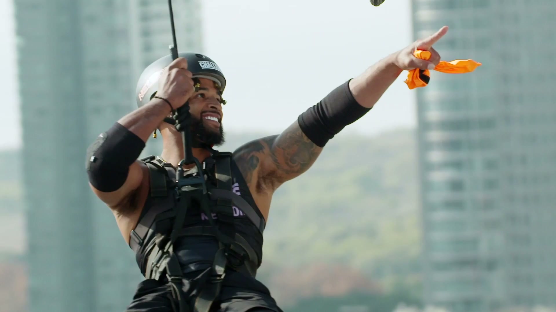 Nelson Thomas in The Challenge, wearing a harness and reaching for something in mid-air.