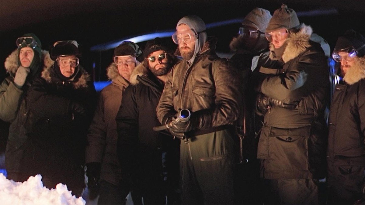 The Thing, several men standing in the snow, one with a flamethrower, all in parkas. 