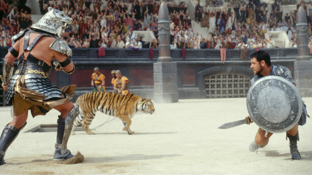 Russel Crowe faces off against a Champion and a lion in the arena in Gladiator