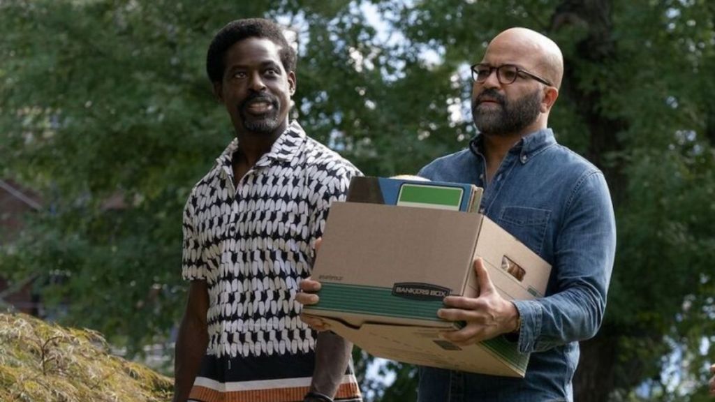 Two African-American men, one of them carrying a box full of things, walk together